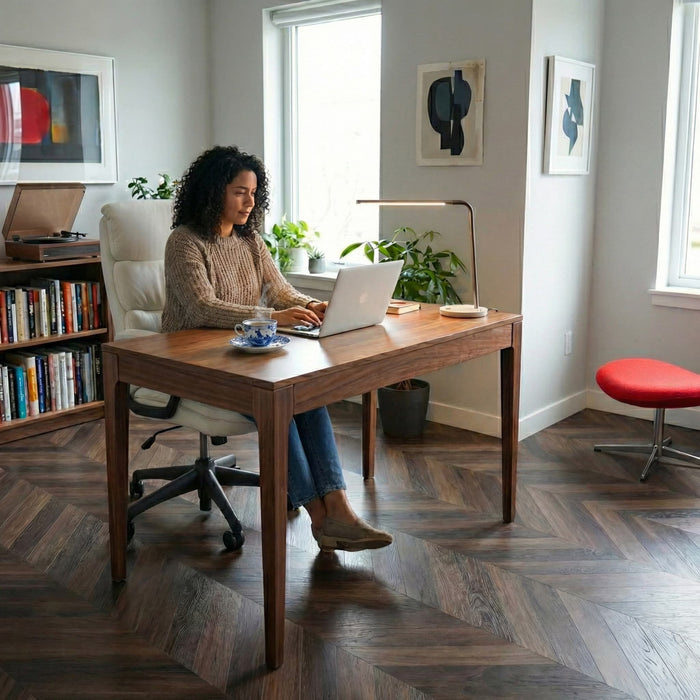 Woman working on a laptop at a wooden desk in a home office setting with Allure chevron flooring.