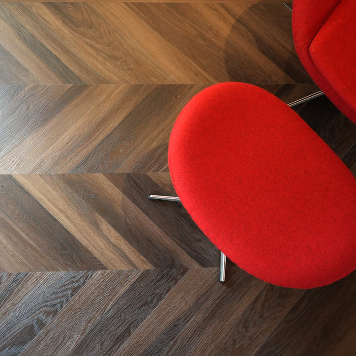 Red chair on a dark chevron wood floor with a herringbone pattern