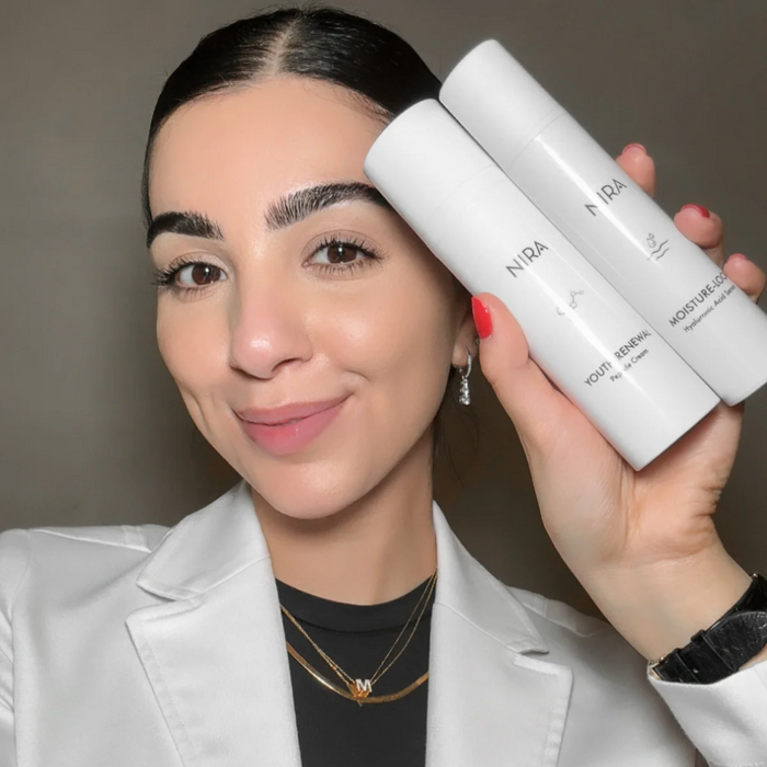 Woman holding NIRA Pro Laser (2nd Gen) & Skincare Bundle serums with clear skin and natural makeup look
